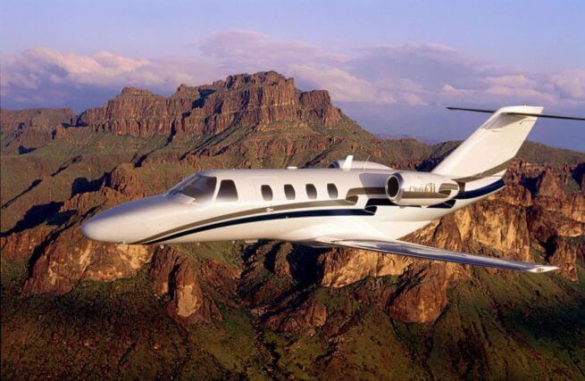 a cessna citation cj1 private jet flying over mountains